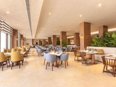 Przestronna restauracja hotelowa z nowoczesnymi krzesłami, stołami i ciepłymi kolorami.