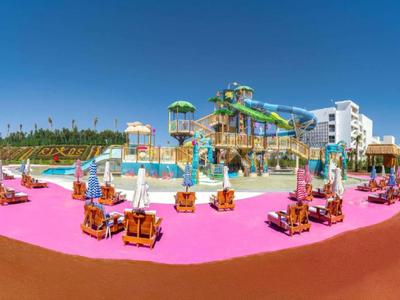 Kolorowy park wodny z zjeżdżalniami i placami zabaw w hotelowym kurorcie pod przejrzystym niebem.
