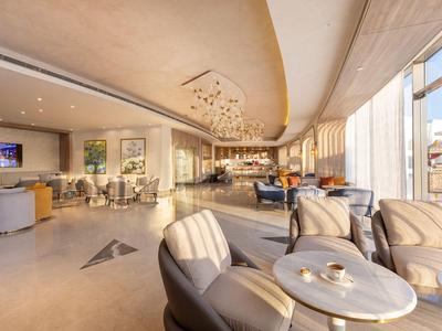 Nowoczesny hol hotelowy z wygodnymi fotelami i dużymi oknami wpuszczającymi dużo światła dziennego.