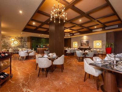 Elegancka restauracja z drewnianym sufitem, ciepłymi tonami i stylowo nakrytymi stołami.