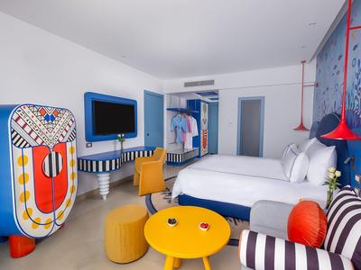 Nowoczesny pokój hotelowy z kolorowymi meblami i czystymi białymi ścianami.