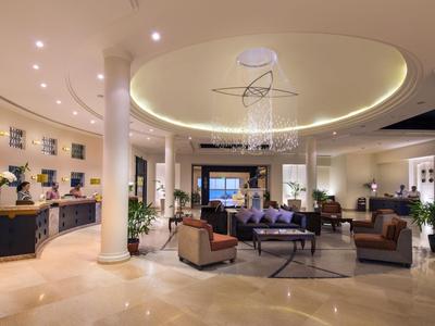 Große Hotellobby mit modernen Möbeln, Rundsäulen und heller Deckenbeleuchtung.
