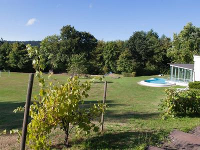 Moderner weißer Bungalow mit Pool in einem großen Garten unter blauem Himmel