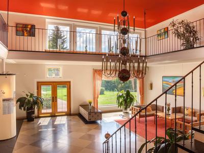 Helles Hotelfoyer mit roten Decken, großen Fenstern und einer Wendeltreppe.