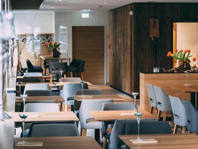 Modernes Restaurant mit Holzwänden, blauen Stühlen und eleganten Tischen, dekoriert mit Blumen.