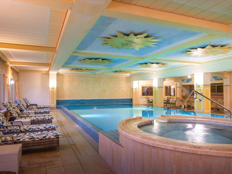 Innen Schwimmbad mit rechteckigem Pool, rundem Whirlpool, Liegen und deckenmalerei.