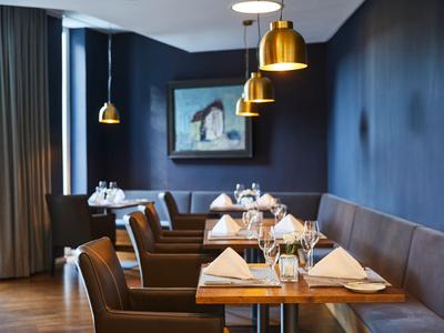 Elegantes Restaurant mit gedeckten Tischen, braunen Stühlen und neutraler Wanddekoration.