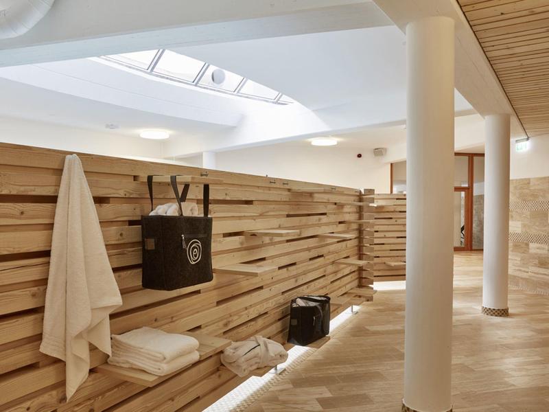 Helle Sauna mit Holzwänden, weißen Säulen, Handtüchern und natürlichem Licht von Oberlicht.