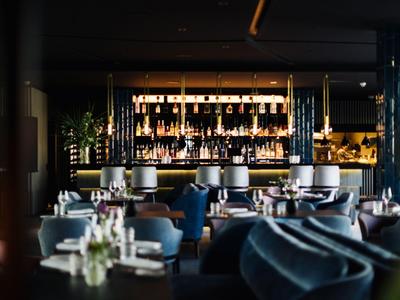 Modernes Restaurant mit eleganter Bar, gemütlichen Sitzecken und gedämpfter Beleuchtung.