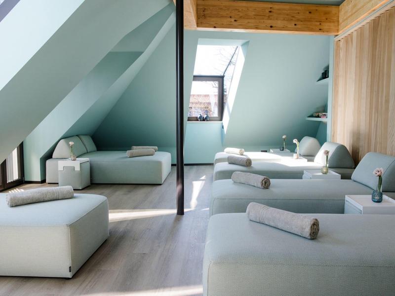 Helles, modernes Zimmer mit blauen Wänden, echtem Holzbalken und weißen bequemen Sofas.