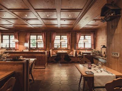 Gemütlicher, rustikaler Restaurantraum mit Holzmöbeln und gedeckten Tischen in einem Hotel.