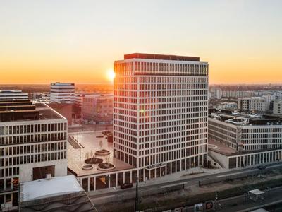 Moderner Bürokomplex bei Sonnenuntergang in einer Großstadt mit klaren Gebäudestrukturen.