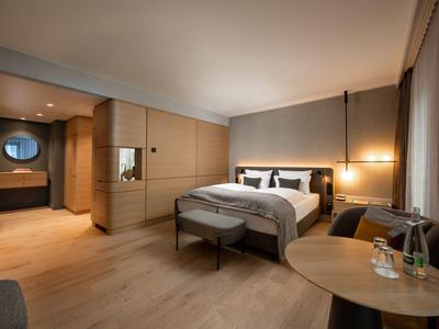 Modernes Hotelzimmer mit Doppelbett, Sitzbereich und warmen Holzakzenten.