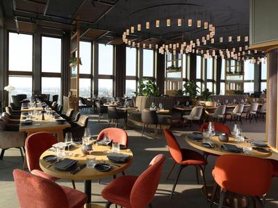 Modernes Restaurant mit großen Fenstern, Rundtischen und orangen Stühlen