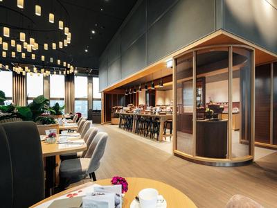 Modernes Restaurant mit eleganten Tischen, Stühlen, Barbereich und gedämpfter Beleuchtung.