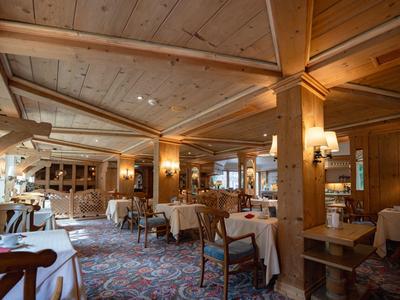 Gemütlicher Restaurantbereich mit Holzbalken, Teppichboden und gedeckten Tischen.