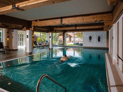 Ein Hallenbad mit hölzernen Balken und großen Fenstern mit Blick auf einen Garten.