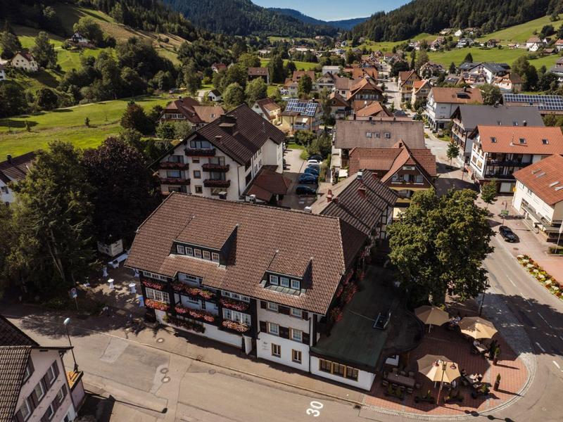 Luftaufnahme eines Dorfes mit traditionellen Häusern und grünen Hügeln im Hintergrund
