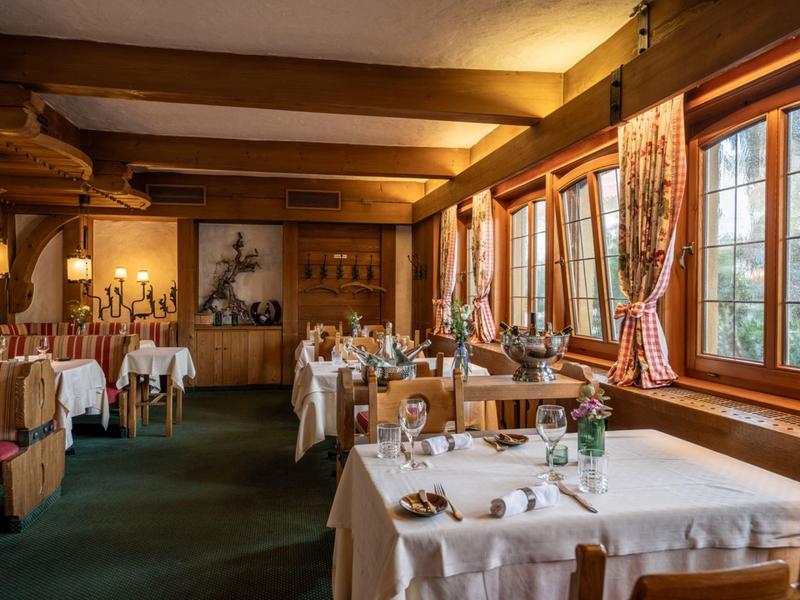 Gemütliches Restaurant mit großen Fenstern, weiß gedeckten Tischen und rustikalem Holzinterieur.