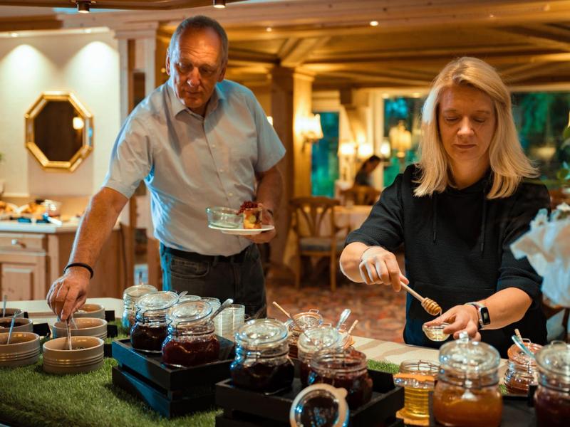 Zwei Personen bedienen sich an einer Auswahl von Marmeladen in einem Restaurant.