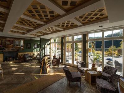 Gemütlicher Lounge-Bereich mit Sesseln und großen Fenstern, die auf eine Terrasse blicken.