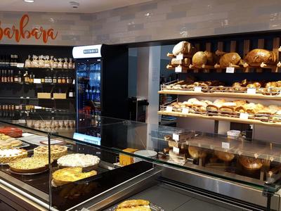 Moderne Bäckerei mit beleuchteten Theken voller verschiedener Backwaren und Kaffeemaschine