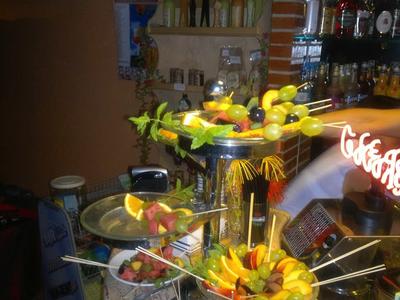 Kolorowe szaszłyki owocowe na wielopoziomowym stojaku w barze.