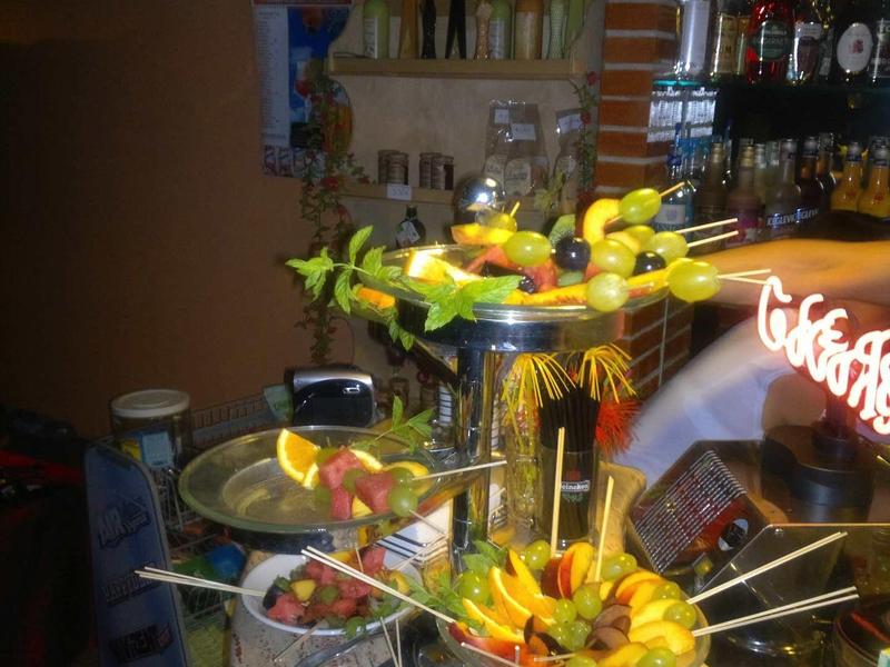 Kolorowe szaszłyki owocowe na wielopoziomowym stojaku w barze.