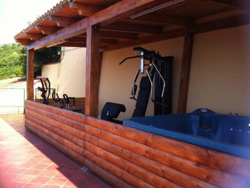 Zadaszony teren z sprzętem fitness i jacuzzi na tarasie.