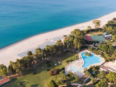 Luftaufnahme eines Resorts mit Pool, Strand und türkisfarbenem Meer.