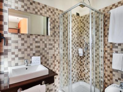 Modernes Badezimmer mit Eckdusche, quadratischen Fliesen, Waschtisch und Handtüchern.