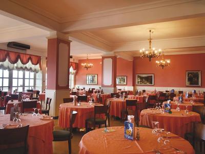 Großer Hotel-Speisesaal mit rot gedeckten Tischen und Kronleuchtern.