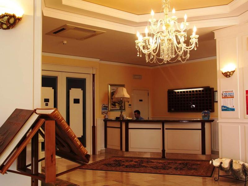 Przytulna recepcja hotelowa z żyrandolem i ladą.