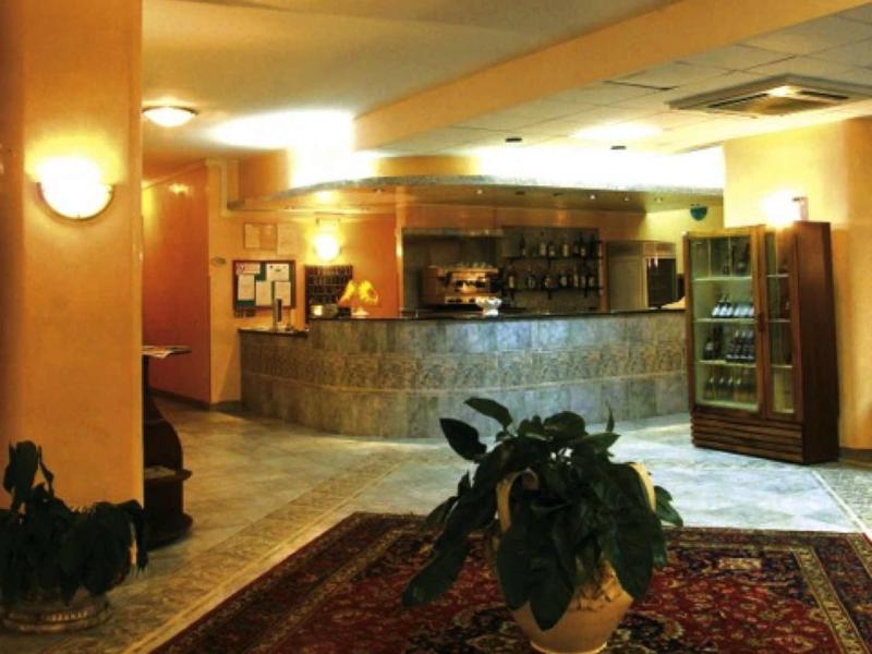 Hall d'hôtel avec tapis, plantes, réception et éclairage doux.