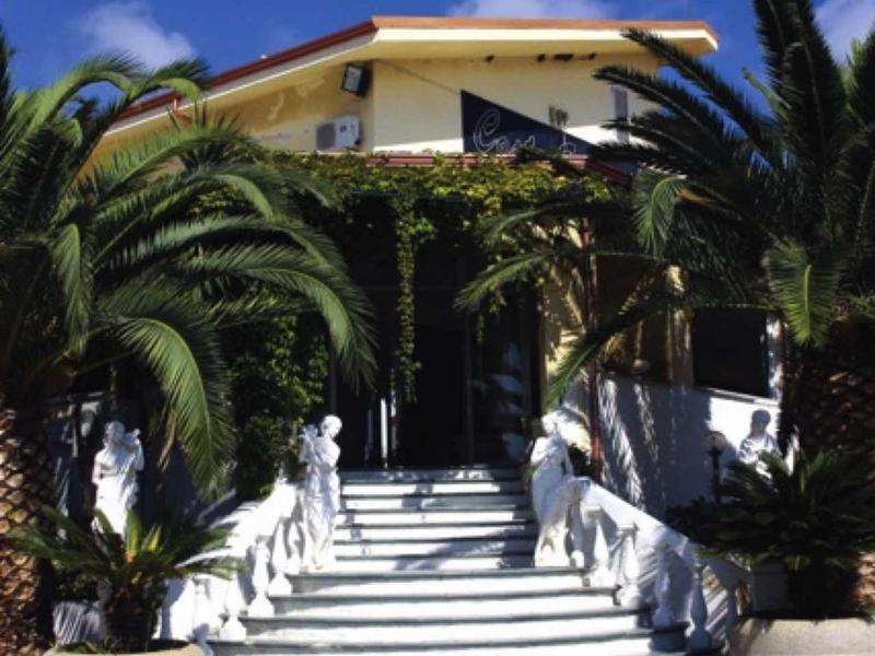 Escalier lumineux mène à une maison aux tuiles rouges, entourée de palmiers.