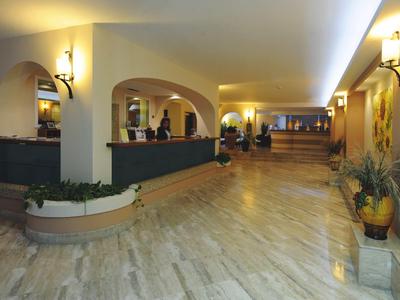 Weitläufige Hotellobby mit Rezeption, Marmorboden und warmem Licht.