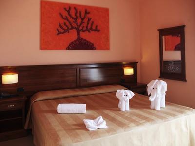 Gemütliches Zimmer mit braunem Bett, vier Lampen, Wandbildern und Handtüchern als Figuren.