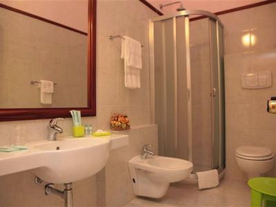 Kleines Badezimmer mit Duschkabine, Waschbecken, Bidet, WC, großem Spiegel und Handtüchern.