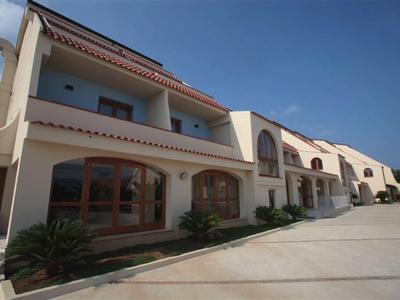 Reihe von hellen Ferienhäusern mit roten Dächern unter blauem Himmel.