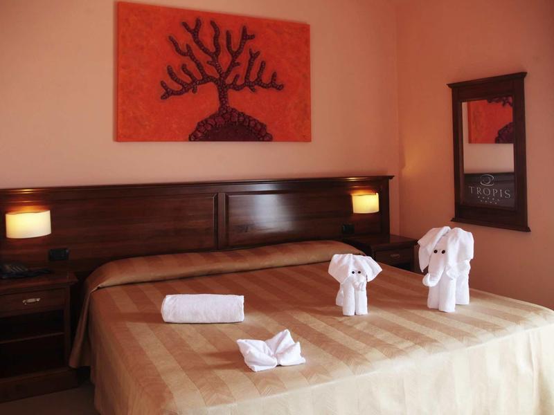 Gemütliches Zimmer mit braunem Bett, vier Lampen, Wandbildern und Handtüchern als Figuren.