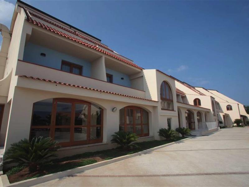 Reihenhäuser mit roten Ziegeldächern, großen Fenstern und einer hellen Fassade an sonnigem Tag.