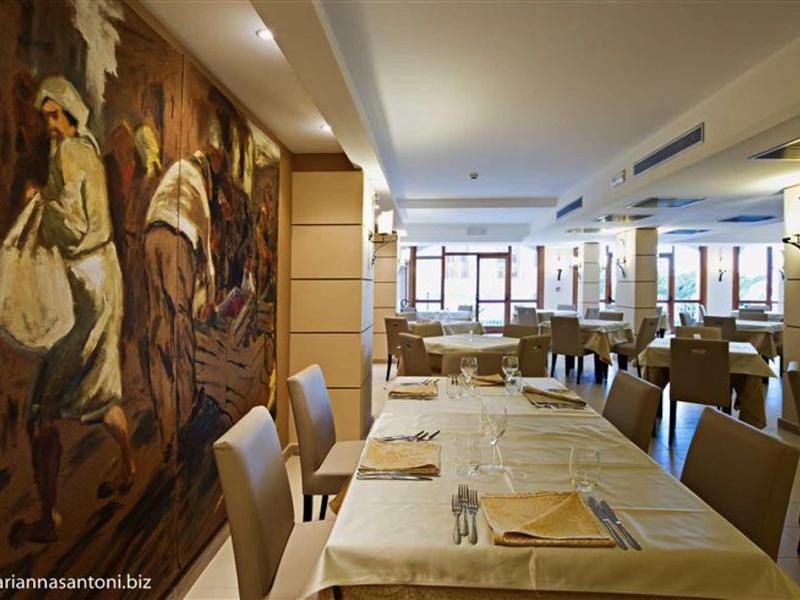 Gemütliches Restaurant mit brauner Wandmalerei, weißen Tischdecken und hellen Stühlen.