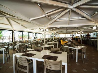 Large open dining area with many white tables and chairs under a vaulted roof.