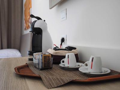 Coffee machine with cups and sugar container on a tray in a hotel room.