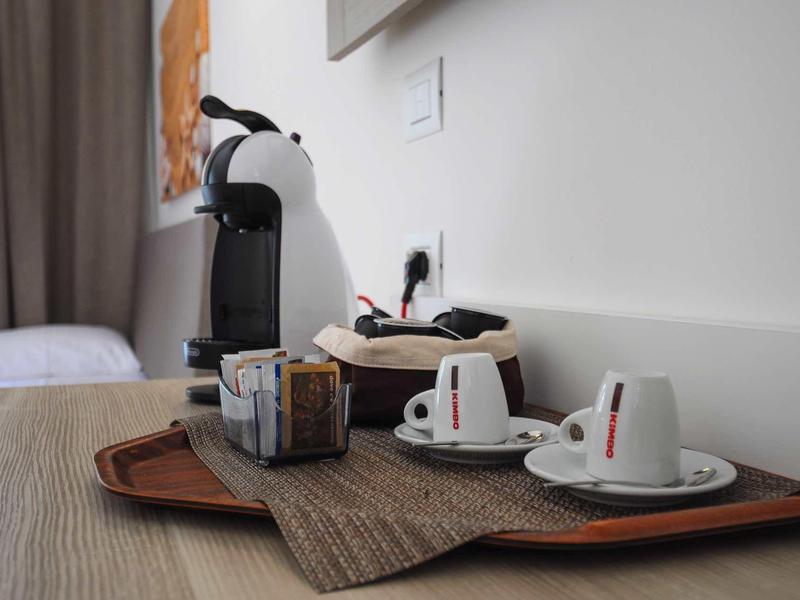 Coffee machine with cups and sugar container on a tray in a hotel room.