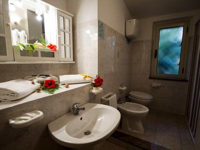 Salle de bain moderne avec lavabo, toilettes, bidet et fleurs décoratives sur l'étagère.