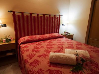 Chambre double confortable avec couverture rouge, tables de chevet et éclairage doux.