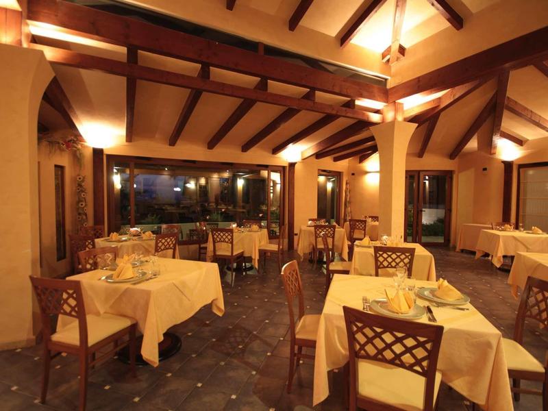 Salle à manger chaleureuse avec poutres en bois et tables dressées sous une lumière douce.