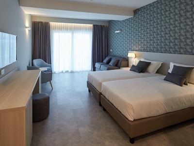 Camera d'hotel moderna con letto matrimoniale, scrivania e ampia finestra con tende.