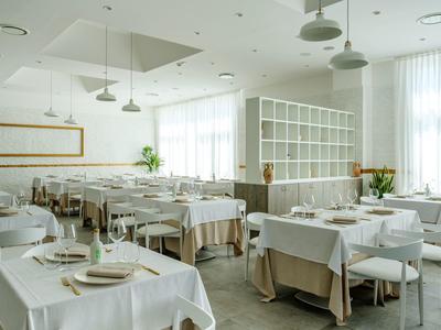 Ristorante luminoso e moderno con tovaglie bianche e tavoli apparecchiati